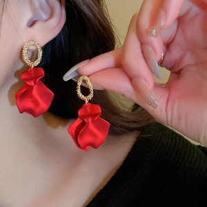 Detail of red matte rose petal earrings with gold textured oval link in French retro style