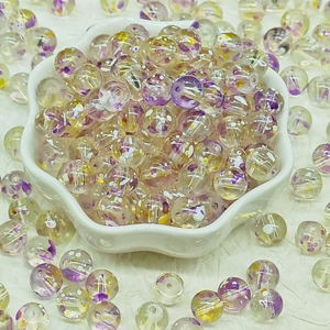 Macro detail of transparent glass flower beads with purple patterns in a white bowl