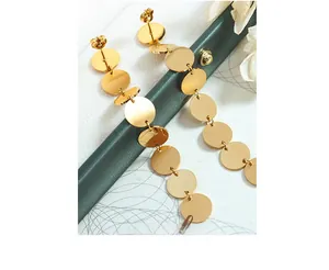 Detailed view of gold circular titanium earrings with brushed texture and layered drop design