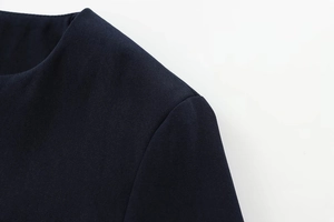 Macro shot of dark textured woven fabric showing shoulder seams and neckline details