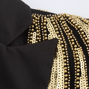 Detailed view of black blazer dress featuring intricate gold beaded embroidery on the shoulder