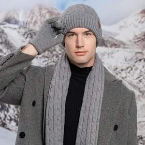 Gray cable-knit winter set with hat scarf and gloves against snowy mountain