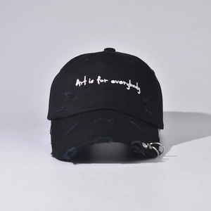 Close-up of distressed black denim baseball cap featuring white embroidery and metal ring