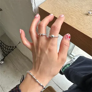Close-up of minimalist S925 sterling silver knotted ring and sleek metallic bone bracelet