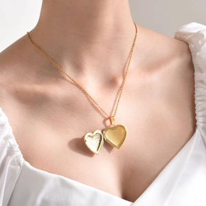 Close-up of gold heart locket pendant necklace worn on the neck of a female model