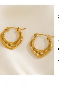 Gros plan détaillé de boucles d'oreilles cœur texturées plaquées or 18 carats sur soie