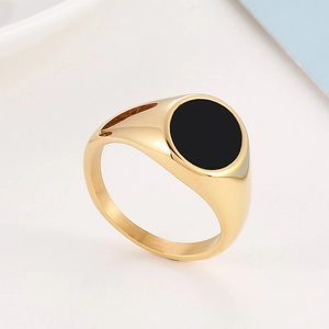 Macro side view of golden stainless steel signet ring with a round black enamel inlay