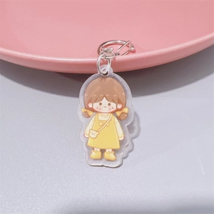 Close-up of cute cartoon girl acrylic keychain with brown pigtails and yellow dress