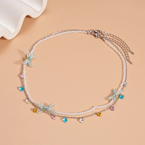 Macro detail of a double-layer bow necklace with zircon beads on a warm peach background