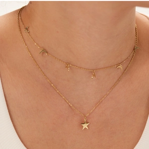 Close-up of double-layer gold necklace featuring crescent moons and star pendant on woman