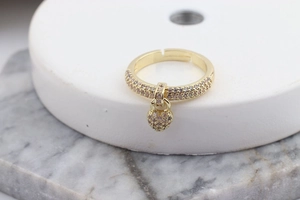 Macro view of gold heart charm ring with white and pink crystal pavé on marble background