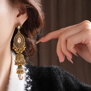 Détail de boucles d'oreilles Jhumka dorées avec cristaux champagne sur un mannequin