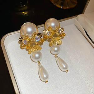 Detail of vintage long gold pearl earrings with flower components and drop pearls