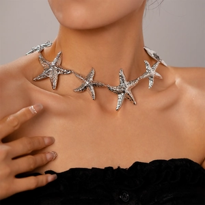Detail of silver starfish link necklace with textured metal surface on a female model