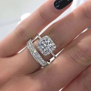 Macro shot of cushion cut halo engagement ring with matching pave wedding band on hand