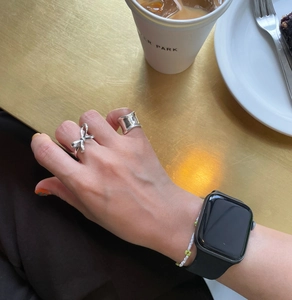 Detail shot of two silver bow and wide band rings on a hand with casual background