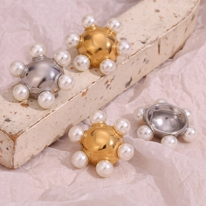 Detail view of gold and silver round stud earrings with pearls on a textured stone surface