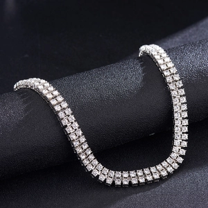 Detail of silver double row tennis chain with sparkling rhinestones on dark textured background