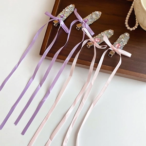 Detail of elegant hair clips with long ribbons and diamond-studded glass beads