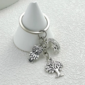 Antique silver keychain with owl, tree of life, and crescent moon charms on a display stand