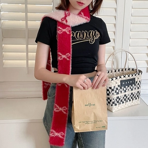 Pink and red plush scarf with woven bow patterns shown in a close-up lifestyle style