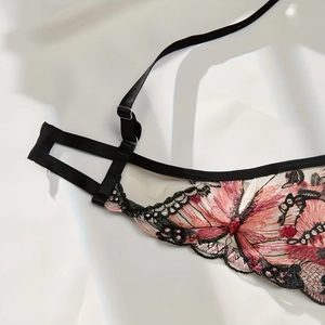 Detailed close-up of pink floral embroidery and delicate lace on black mesh lingerie