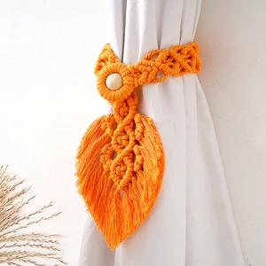 Detail of orange leaf-shaped woven cotton curtain tieback with a natural wooden bead