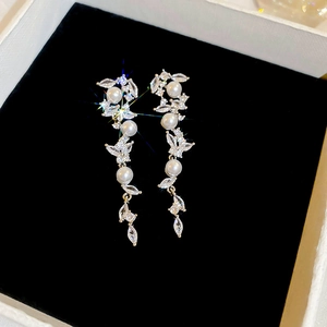 Macro shot of silver pearl tassel earrings with zircons in a velvet lined jewelry box