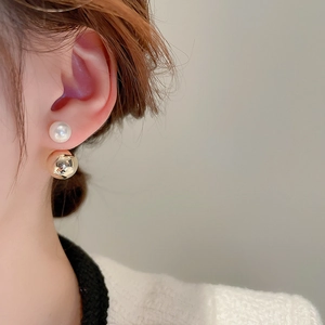 Close-up of model wearing gold spherical and pearl double-sided stud earrings