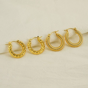 Detail view of gold titanium steel hoop earrings with textured and geometric patterns