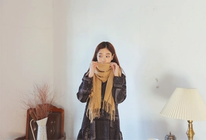 Detail of ginger cashmere-feel scarf with elegant tassels and fine texture on a model
