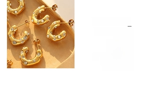 Detail view of gold-plated C-shaped earrings with lava texture, pearls, and zircons
