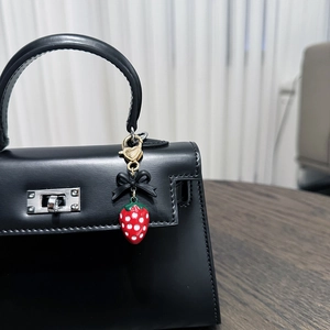 Zinc alloy strawberry charm with black bow and golden heart clasp on handbag