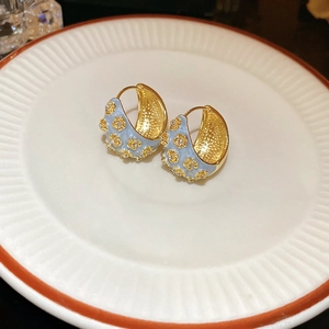 French vintage light blue enamel flower earrings with gold accents on a white plate