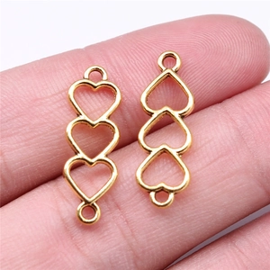 Macro shot of gold hollow triple heart connectors held by hand for jewelry DIY