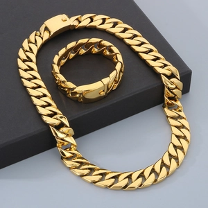 Detail view of 20mm gold hip hop Cuban link chain necklace and bracelet set on a grey stand