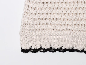 Detailed macro view of cream crochet knit texture with black wavy edge finish