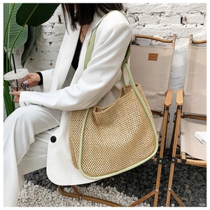 Straw tote bag with light green straps shown in a minimalist outdoor lifestyle setting