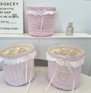 Close-up of pink quilted fabric storage bins with heart lace trim and drawstring bows
