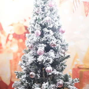 Pink and silver Christmas ornaments with diverse textures hanging on a snowy tree