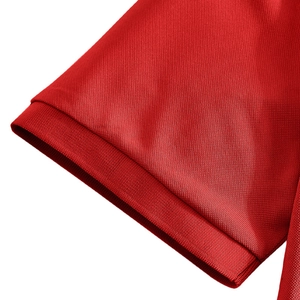 Detail of red polo shirt sleeve cuff showing pique texture and ribbing stitching
