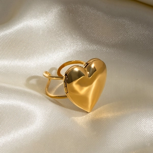 Détail macro d'une bague médaillon coeur doré avec charnière sur fond de soie douce
