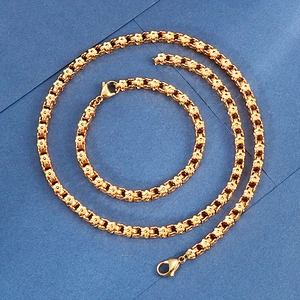 Macro view of gold-tone stainless steel floral link necklace and bracelet with lobster clasps