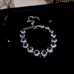 Detailed close-up of a silver bracelet with green emerald stones and lobster clasp