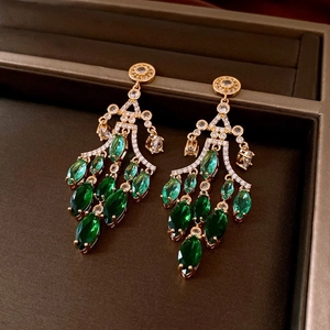 Detailed close-up of vintage gold earrings with emerald green stones and tassels