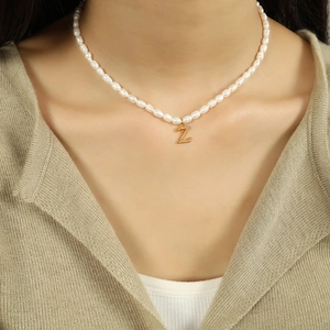 Elegant pearl necklace with golden letter Z titanium pendant worn on a female model
