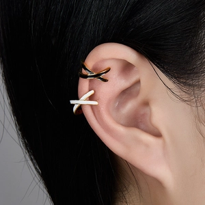 Close-up of double layer enamel ear cuffs in black, white and gold on model ear