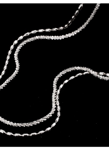 Macro detail of silver double-layered necklace featuring rice bead and shimmering fine chains