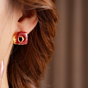 Detail view of a French vintage square red enamel earring with gold metallic edges on model