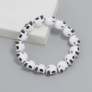 Macro shot of white skull beads bracelet with black details on grey background